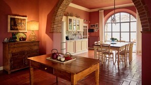A cozy kitchen with a wooden table, a brick archway, and a large window. - Villa Marliana - Luxury Villa with private pool (Cerreto Guidi)
