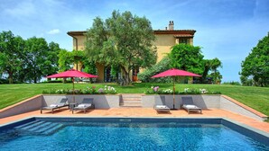A swimming pool with lounge chairs and umbrellas, surrounded by a well-maintained lawn and a large building in the background. - Villa Marliana - Luxury Villa with private pool (Cerreto Guidi)
