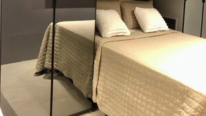 Een slaapkamer met een bed, een aan de muur bevestigde televisie en een inloopkast met schuifdeuren.