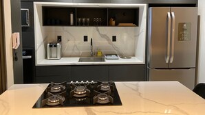 Een moderne keuken met een ingebouwde gasplaat, een roestvrijstalen koelkast en een marmeren aanrechtblad.
