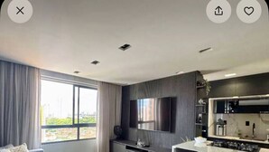 Een moderne woonkamer met een bank, salontafel, televisie en een keukenbar.