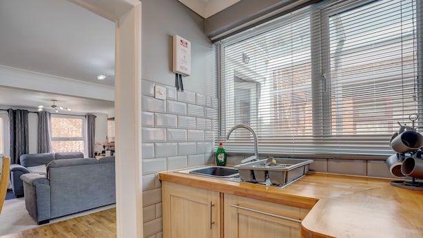 A modern kitchen with a wooden countertop, a sink, and a window with blinds.