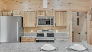 A kitchen with wooden cabinets, a stainless steel refrigerator, a microwave, and an oven.