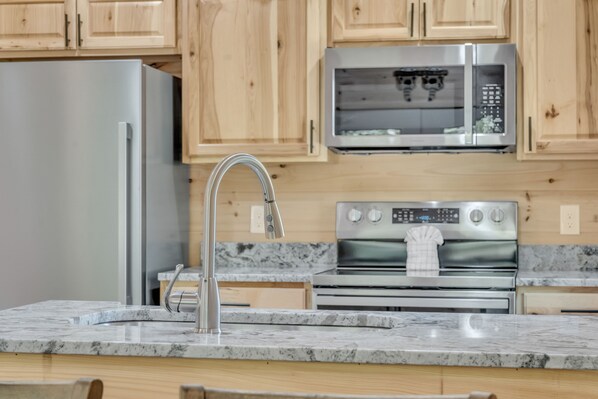 Une cuisine moderne avec des meubles en bois, des appareils électroménagers en acier inoxydable et des plans de travail en granit.
