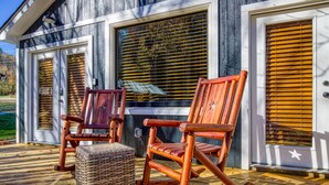 A wooden deck with rocking chairs and a wicker ottoman.
