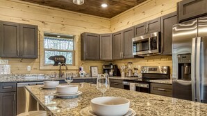 A kitchen with granite countertops, stainless steel appliances, and dark wooden cabinets.