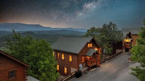 Eine Blockhütte mit Veranda, Auffahrt und Sternenhimmel.