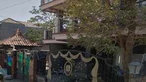 A residential area with a gated entrance, a tiled roof, and a tree. - OYO 3887 Potreh Mastekah 2 (Banten)