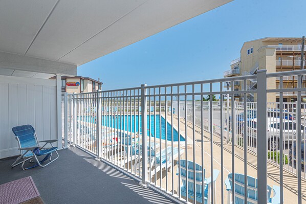 A balcony with a pool view, white railing, and blue chairs. - Large Ocean Front 2bed/2bath with pool. A perfect fit for large family! Sleep 10 (Ocean City)