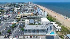 A multi-story hotel with a rooftop pool, located near a beach with a sandy shore and umbrellas. - Large Ocean Front 2bed/2bath with pool. A perfect fit for large family! Sleep 10 (Ocean City)