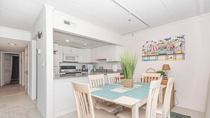 Een moderne keuken met witte kasten, een magnetron en een eethoek met een tafel en stoelen.
