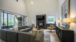 Una sala de estar moderna con un sofá seccional, una chimenea y grandes ventanales que ofrecen vistas al exterior.