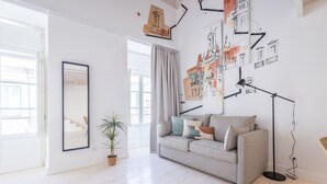 A modern living room with a grey sofa, a floor lamp, and a large mirror. - Suits Boutique Arco - Mezanino apartment by HD (Faro)