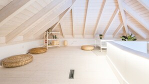 A high-ceilinged room with wooden beams, a white reception desk, wicker baskets, and a small shelf with plants. - Suits Boutique Ala - Studio mezanino by HD (Faro)