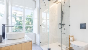 A modern bathroom with a glass-enclosed shower, a white sink, and a toilet. - Suits Boutique Ala - Studio mezanino by HD (Faro)