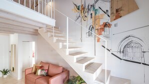 Un interno moderno con una scala, un divano rosa e una parete con disegni architettonici.