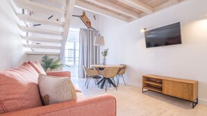 Un soggiorno moderno con divano, tavolo da pranzo, sedie e TV a parete.