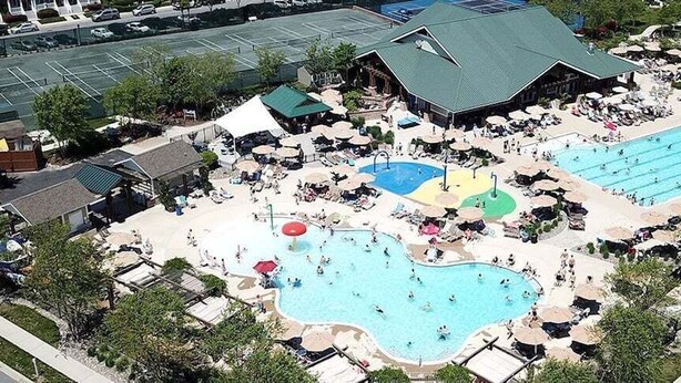 A resort with multiple swimming pools, sun loungers, and a large building with a green roof.