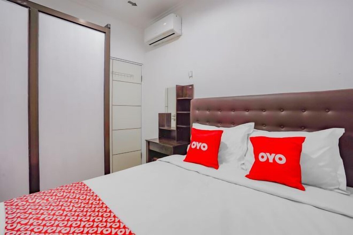 A hotel room with a bed, a wardrobe, a mirror, and a shelf.