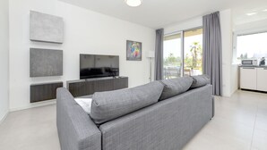 A modern living room with a grey sofa, a flat-screen TV, and artwork on the walls.
