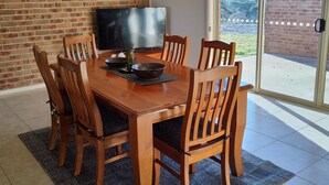 Un espace repas avec un mur en briques, un téléviseur à écran plat et une vue sur l’extérieur grâce à une porte vitrée.