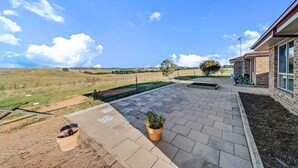 Une terrasse avec un sol en briques, une plante en pot et un petit espace aménagé en jardin.