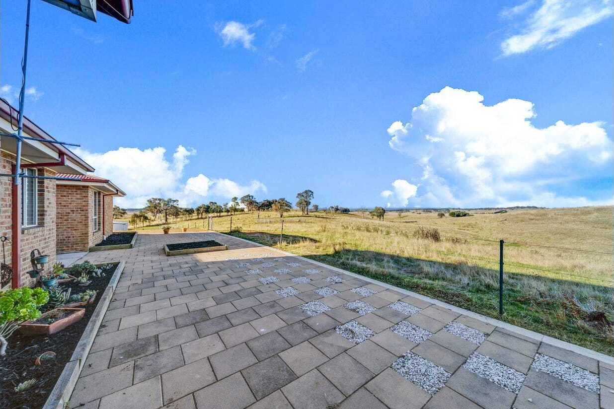 A paved walkway leading to a house with a brick exterior and a garden.