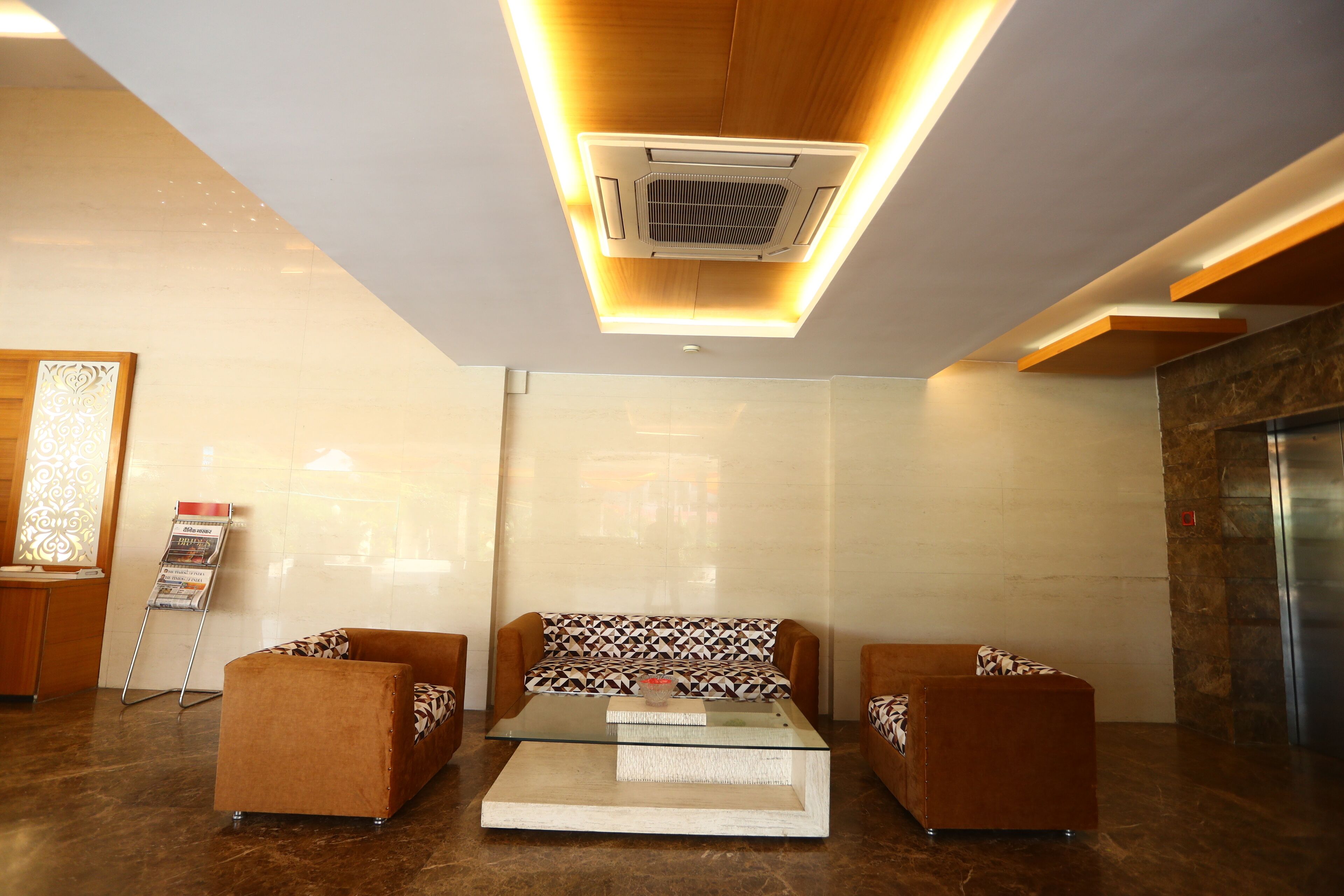 A lobby with a sofa set, a glass coffee table, and a standing air conditioner.