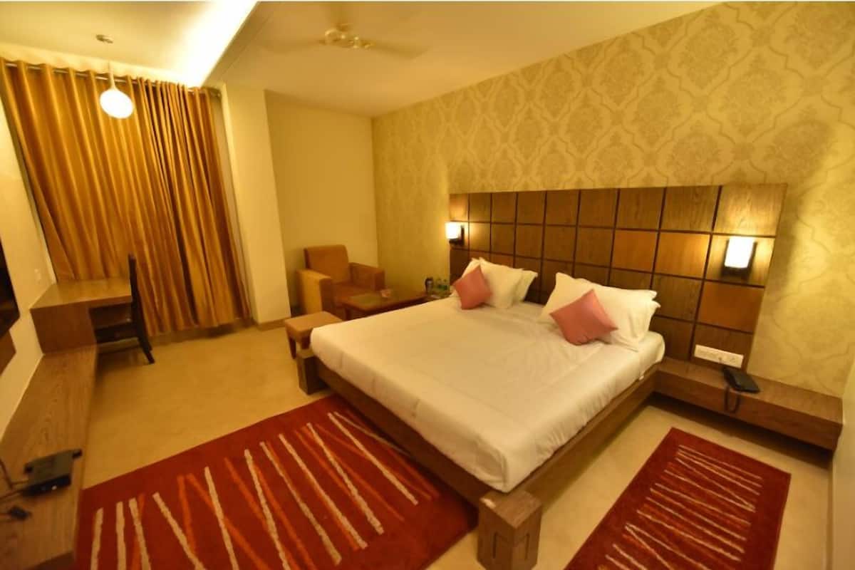 Une chambre d’hôtel avec un grand lit, deux tables de chevet, une chaise et un bureau.