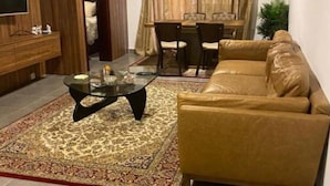 Uma sala de estar com sofá, mesa de centro, televisão e um espaço de jantar com mesa e cadeiras.