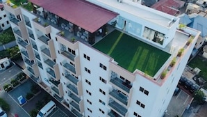 Um edifício com vários andares, varandas, terraço no telhado e área de estacionamento.