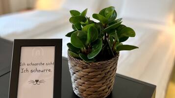 Un letrero en marco, con texto y una planta en maceta sobre una mesita de noche.