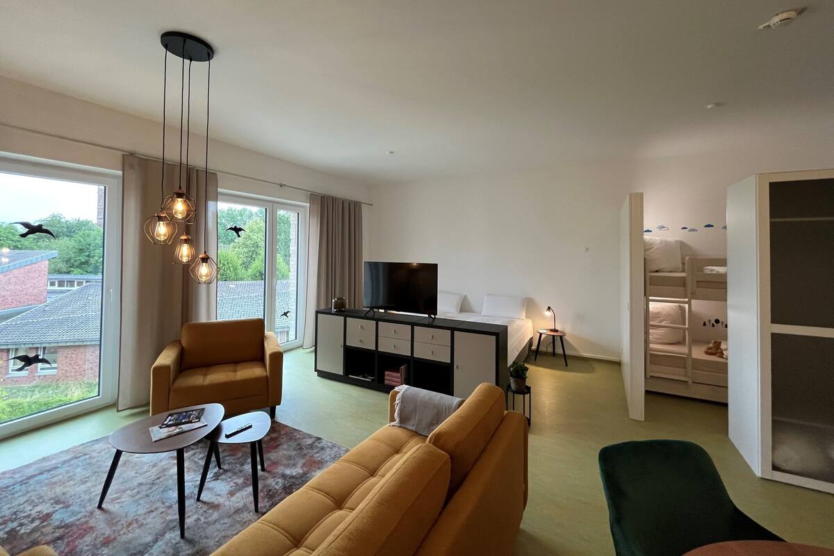 A modern living room with a sofa, a coffee table, a TV, and a balcony with a view of the city.