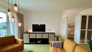 Un salon moderne avec un canapé, une table basse et un téléviseur posé sur un meuble.
