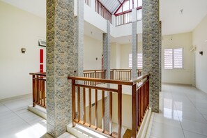 A spacious interior with a high ceiling, stone pillars, wooden railings, and a tiled floor. - OYO 90173 Innapp Tenggilis Family Residence (Surabaya)