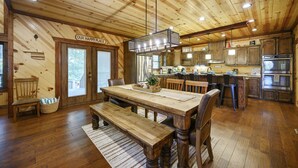 Un intérieur en bois comprenant un coin repas, une cuisine et une enseigne sur laquelle on peut lire : « NOTRE PETIT COIN DE BONHEUR ».