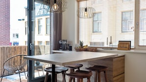 Een moderne keuken met een groot kookeiland, houten krukken en uitzicht op buiten.