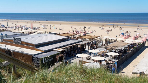 Een hotel aan het strand met terras, een promenade en uitzicht op het strand en de zee.