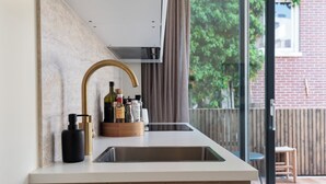 Een moderne keuken met een wit aanrecht, een gouden kraan en een houten kast.