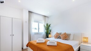 A modern hotel room with a large bed, a nightstand, a wardrobe, and a window with curtains. - City Centre Ocean View Apartment (Lagos)