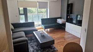 A modern living room with a sofa, a coffee table, and a TV. - Immaculate 1-bed Apartment in London (London)
