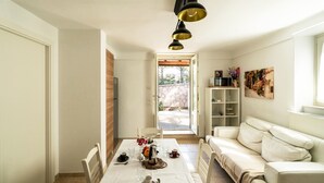 A dining area with a table set for two, a sofa, and a bookshelf.
