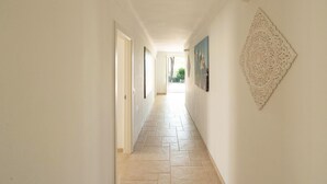 A hallway with a tiled floor, white walls, and a door at the end.