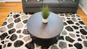 Une table basse ronde, ornée d’une plante au centre, posée sur un tapis à motifs.