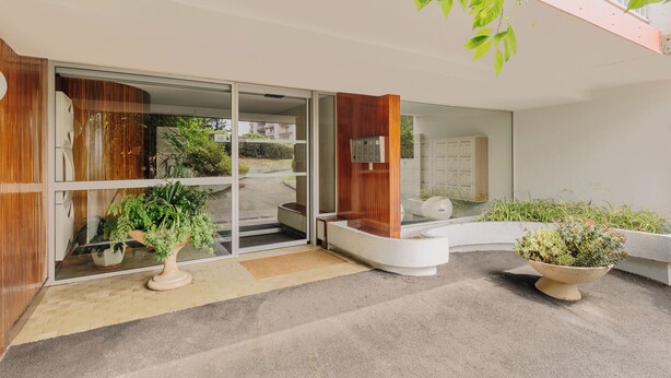 A modern building entrance with glass doors, a wooden reception desk, and potted plants. - Sixties 64 :  2 bedrooms apartment with a balcony and parking in Biarritz (Biarritz)