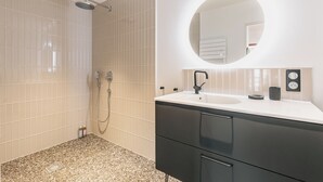 A modern bathroom with a shower, a sink with a mirror, and a vanity with drawers. - Sixties 64 :  2 bedrooms apartment with a balcony and parking in Biarritz (Biarritz)