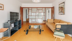 A modern living room with a glass coffee table, a sofa, a bookshelf, and a television. - Sixties 64 :  2 bedrooms apartment with a balcony and parking in Biarritz (Biarritz)