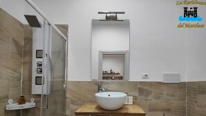 A modern bathroom with a large mirror, a white sink, a toilet, and a shower area. - Studio apartment in Sorrento Peninsula, 300 meters from the sea and free beach (Castellammare di Stabia)