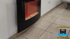 A modern fireplace with a glass front, tiled floor, and a chair in the corner. - Studio apartment in Sorrento Peninsula, 300 meters from the sea and free beach (Castellammare di Stabia)