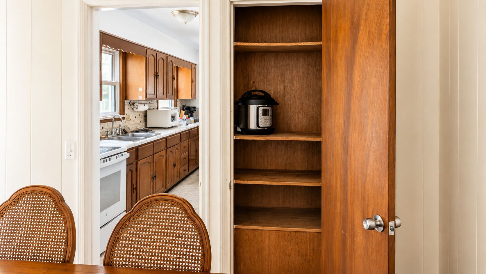 A kitchen with wooden cabinets, a built-in oven, and a coffee maker on a shelf.